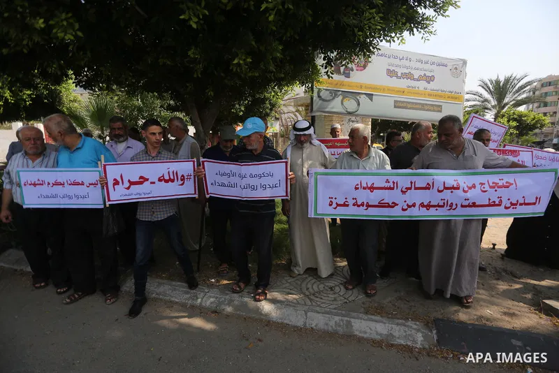 Palestinian Martyrs Families hold placards during a protest demanding their salaries in Gaza city on July 26, 2017. Photo by Mohammed Asad