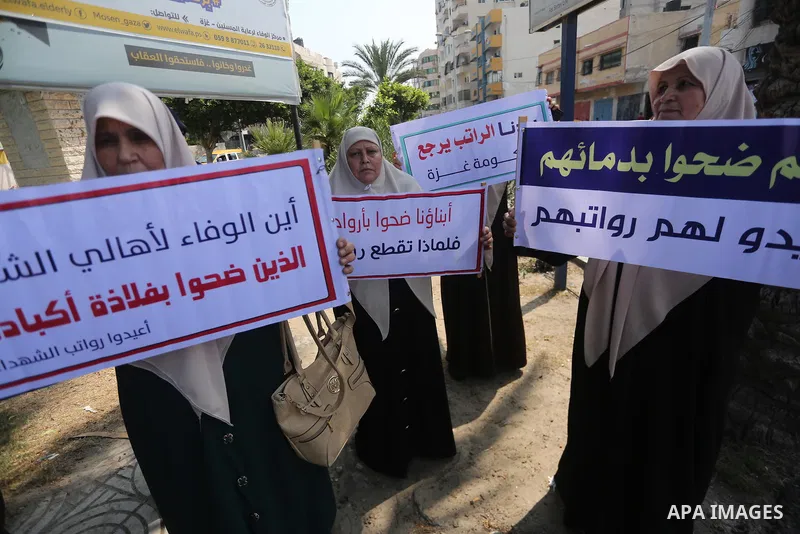 Palestinian Martyrs Families hold placards during a protest demanding their salaries in Gaza city on July 26, 2017. Photo by Mohammed Asad
