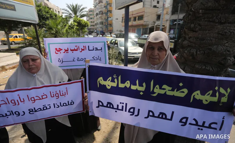 Palestinian Martyrs Families hold placards during a protest demanding their salaries in Gaza city on July 26, 2017. Photo by Mohammed Asad