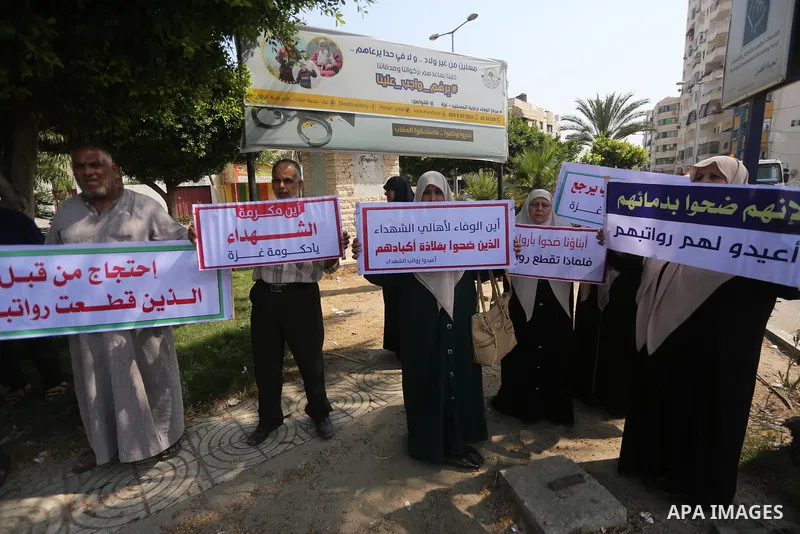 Palestinian Martyrs Families hold placards during a protest demanding their salaries in Gaza city on July 26, 2017. Photo by Mohammed Asad