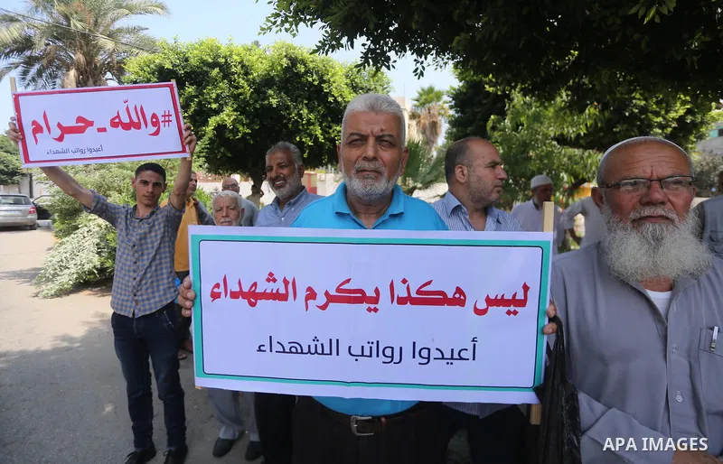Palestinian Martyrs Families hold placards during a protest demanding their salaries in Gaza city on July 26, 2017. Photo by Mohammed Asad