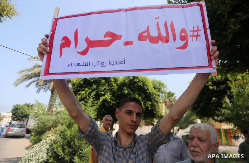 Palestinian Martyrs Families hold placards during a protest demanding their salaries in Gaza city on July 26, 2017. Photo by Mohammed Asad