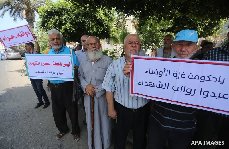 Palestinian Martyrs Families hold placards during a protest demanding their salaries in Gaza city on July 26, 2017. Photo by Mohammed Asad