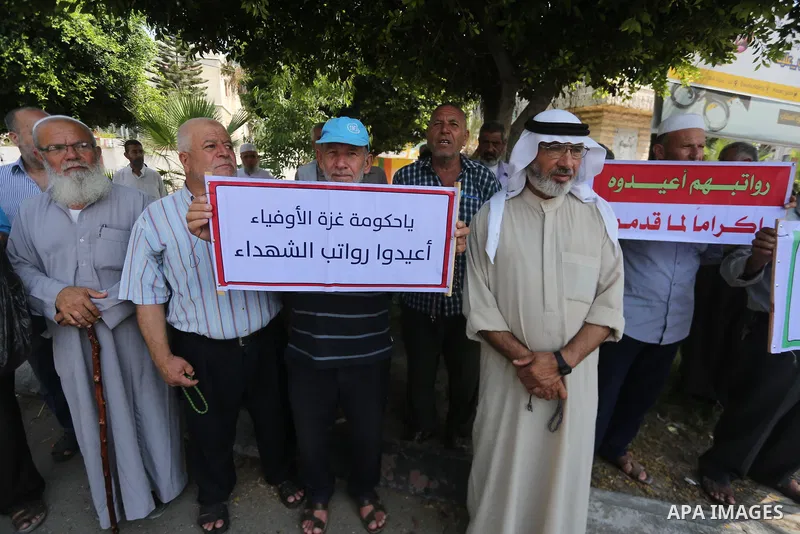 Palestinian Martyrs Families hold placards during a protest demanding their salaries in Gaza city on July 26, 2017. Photo by Mohammed Asad