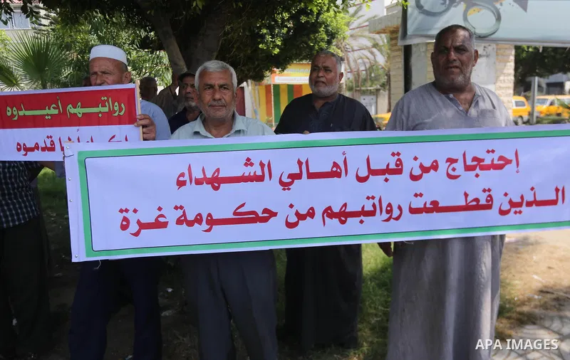 Palestinian Martyrs Families hold placards during a protest demanding their salaries in Gaza city on July 26, 2017. Photo by Mohammed Asad
