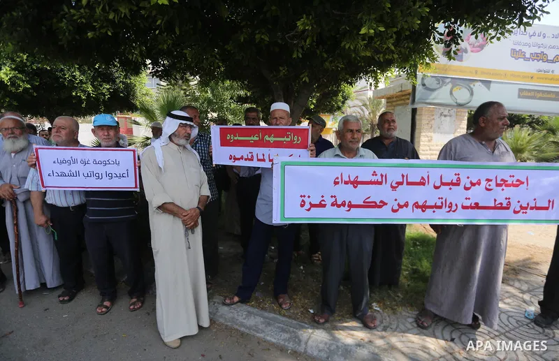 Palestinian Martyrs Families hold placards during a protest demanding their salaries in Gaza city on July 26, 2017. Photo by Mohammed Asad