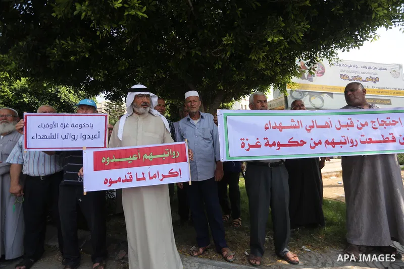 Palestinian Martyrs Families hold placards during a protest demanding their salaries in Gaza city on July 26, 2017. Photo by Mohammed Asad