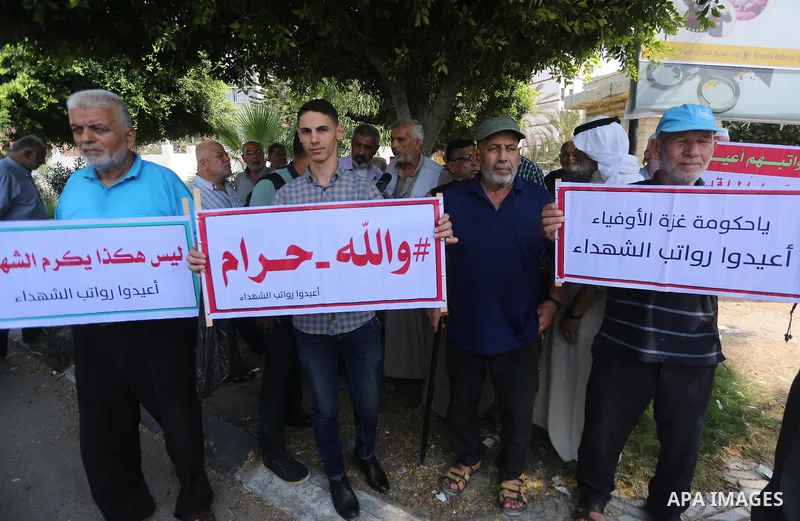 Palestinian Martyrs Families hold placards during a protest demanding their salaries in Gaza city on July 26, 2017. Photo by Mohammed Asad