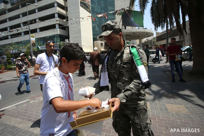 A Palestinian security man distributes sweets to people in the street, as a celebration of the victory at Al-Aqsa Mosque, in the West Bank City of Hebron, on July 27, 2017. Israel removed security apparatus from the entr...