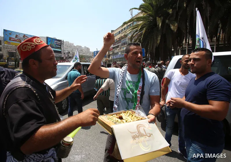 A Palestinian man distributes sweets to people in the street, as a celebration of the victory at Al-Aqsa Mosque, in the West Bank City of Hebron, on July 27, 2017. Israel removed security apparatus from the entrance to t...