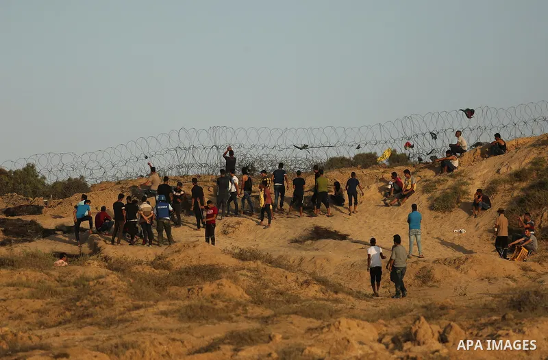 Palestinian protesters take cover during clashes with Israeli troops near the border between Israel and Central Gaza Strip July 28, 2017. Israeli troops shot dead a Palestinian teenager and wounded seven others during cl...