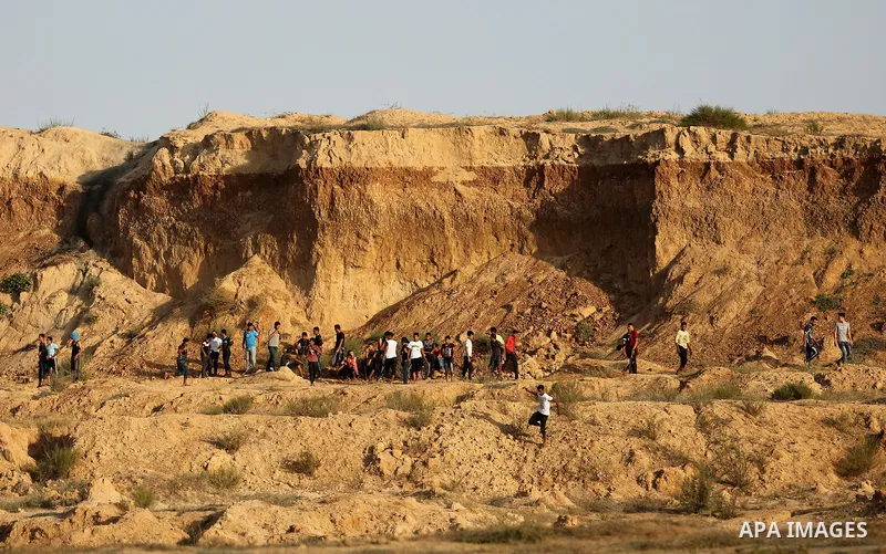 Palestinian protesters take cover during clashes with Israeli troops near the border between Israel and Central Gaza Strip July 28, 2017. Israeli troops shot dead a Palestinian teenager and wounded seven others during cl...