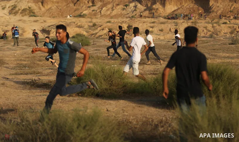 Palestinian protesters take cover during clashes with Israeli troops near the border between Israel and Central Gaza Strip July 28, 2017. Israeli troops shot dead a Palestinian teenager and wounded seven others during cl...