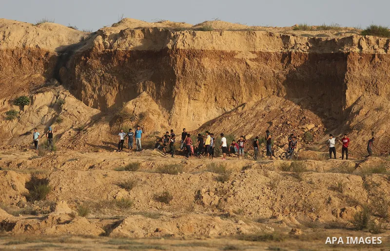 Palestinian protesters take cover during clashes with Israeli troops near the border between Israel and Central Gaza Strip July 28, 2017. Israeli troops shot dead a Palestinian teenager and wounded seven others during cl...