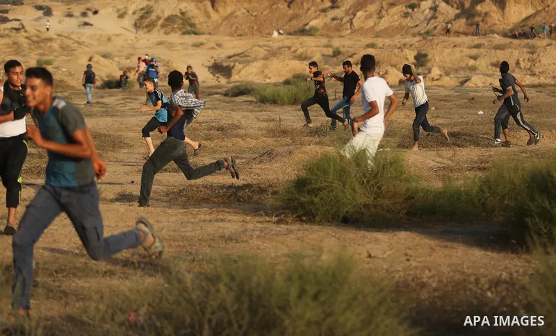 Palestinian protesters take cover during clashes with Israeli troops near the border between Israel and Central Gaza Strip July 28, 2017. Israeli troops shot dead a Palestinian teenager and wounded seven others during cl...