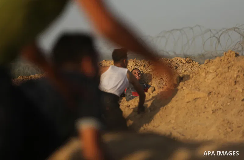 Palestinian protesters take cover during clashes with Israeli troops near the border between Israel and Central Gaza Strip July 28, 2017. Israeli troops shot dead a Palestinian teenager and wounded seven others during cl...