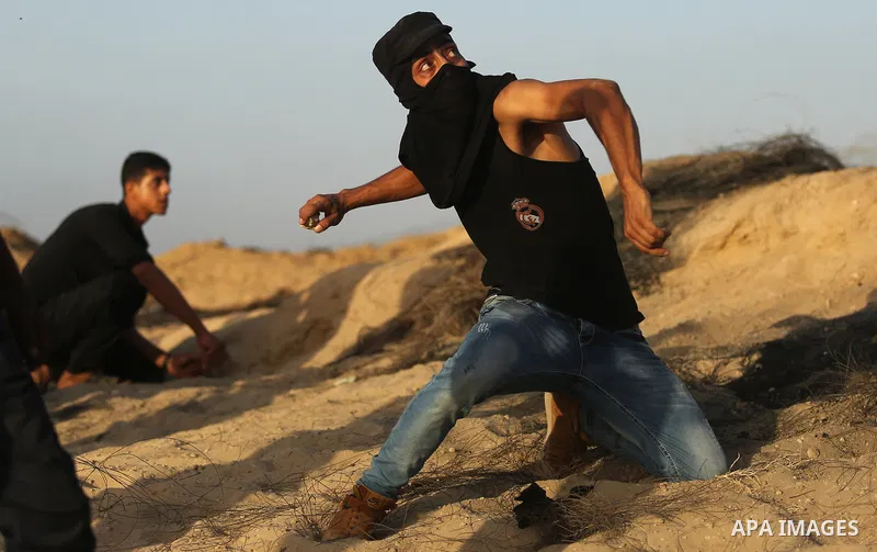 A Palestinian protester uses a slingshot to hurl stones towards Israeli security forces during clashes near the border between Israel and Central Gaza Strip July 28, 2017. Israeli troops shot dead a Palestinian teenager...