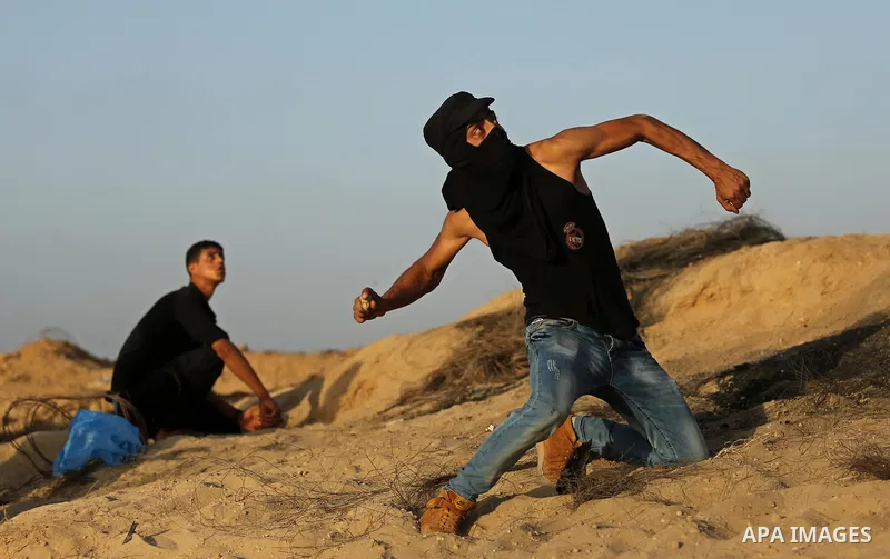 A Palestinian protester uses a slingshot to hurl stones towards Israeli security forces during clashes near the border between Israel and Central Gaza Strip July 28, 2017. Israeli troops shot dead a Palestinian teenager...