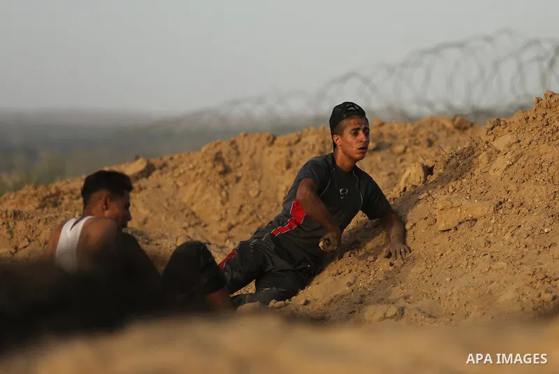 Palestinian protesters take cover during clashes with Israeli troops near the border between Israel and Central Gaza Strip July 28, 2017. Israeli troops shot dead a Palestinian teenager and wounded seven others during cl...