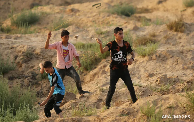 Palestinian protesters take cover during clashes with Israeli troops near the border between Israel and Central Gaza Strip July 28, 2017. Israeli troops shot dead a Palestinian teenager and wounded seven others during cl...