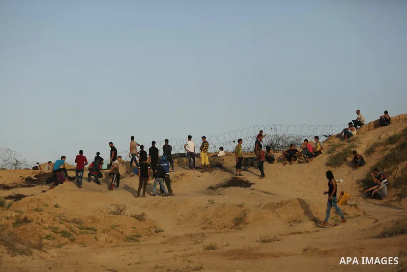Palestinian protesters take cover during clashes with Israeli troops near the border between Israel and Central Gaza Strip July 28, 2017. Israeli troops shot dead a Palestinian teenager and wounded seven others during cl...