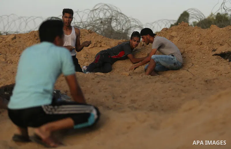 Palestinian protesters take cover during clashes with Israeli troops near the border between Israel and Central Gaza Strip July 28, 2017. Israeli troops shot dead a Palestinian teenager and wounded seven others during cl...
