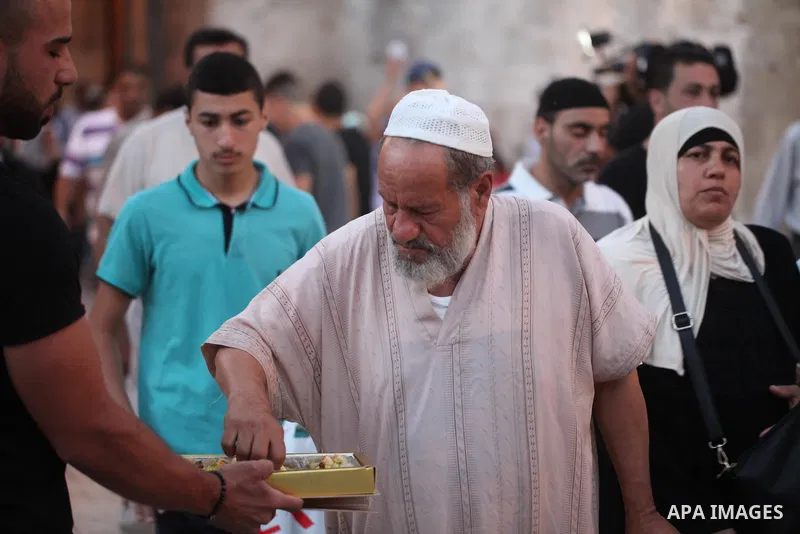 A Palestinian man distributes sweets to people as part of celebrations marking Israel's removal of all security measures it had installed at the compound known to Muslims as Noble Sanctuary and to Jews as Temple Mount, i...