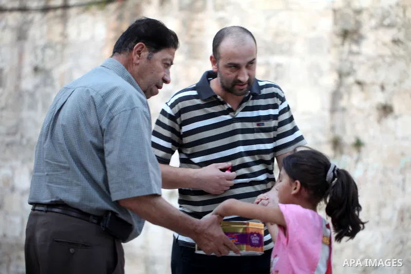 A Palestinian man distributes sweets to people as part of celebrations marking Israel's removal of all security measures it had installed at the compound known to Muslims as Noble Sanctuary and to Jews as Temple Mount, i...