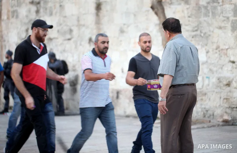 A Palestinian man distributes sweets to people as part of celebrations marking Israel's removal of all security measures it had installed at the compound known to Muslims as Noble Sanctuary and to Jews as Temple Mount, i...