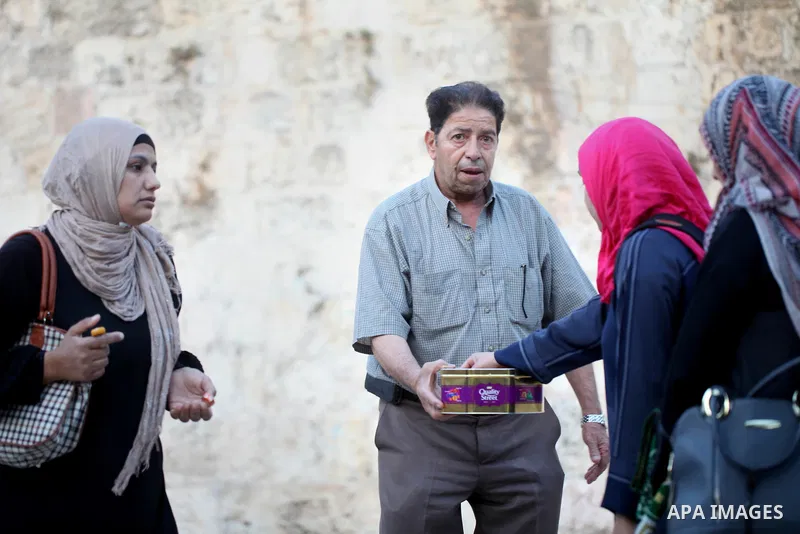 A Palestinian man distributes sweets to people as part of celebrations marking Israel's removal of all security measures it had installed at the compound known to Muslims as Noble Sanctuary and to Jews as Temple Mount, i...