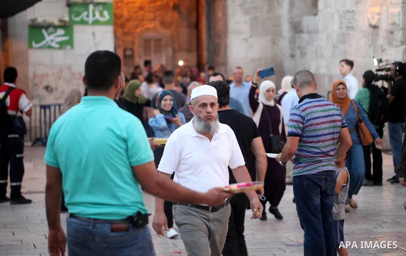 A Palestinian man distributes sweets to people as part of celebrations marking Israel's removal of all security measures it had installed at the compound known to Muslims as Noble Sanctuary and to Jews as Temple Mount, i...