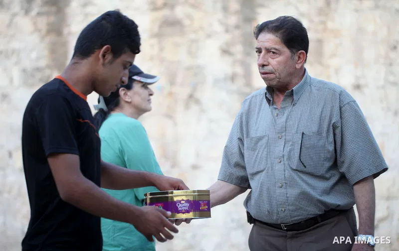 A Palestinian man distributes sweets to people as part of celebrations marking Israel's removal of all security measures it had installed at the compound known to Muslims as Noble Sanctuary and to Jews as Temple Mount, i...