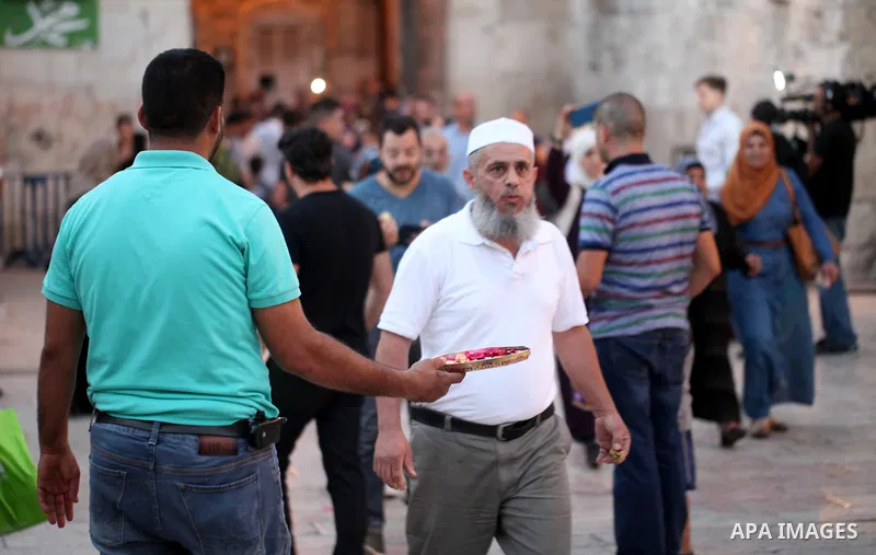 A Palestinian man distributes sweets to people as part of celebrations marking Israel's removal of all security measures it had installed at the compound known to Muslims as Noble Sanctuary and to Jews as Temple Mount, i...
