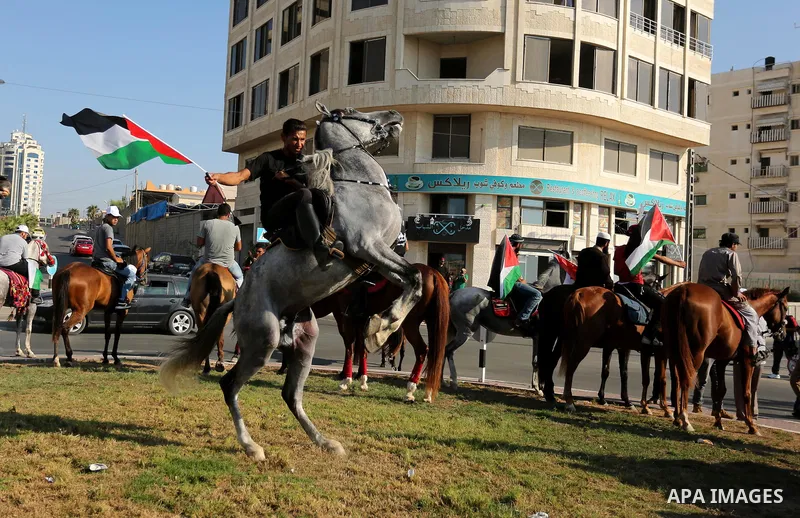 Palestinians hold the national flags as they ride horses during parade of horses in Gaza city on August 2, 2017. Photo by Ashraf Amra