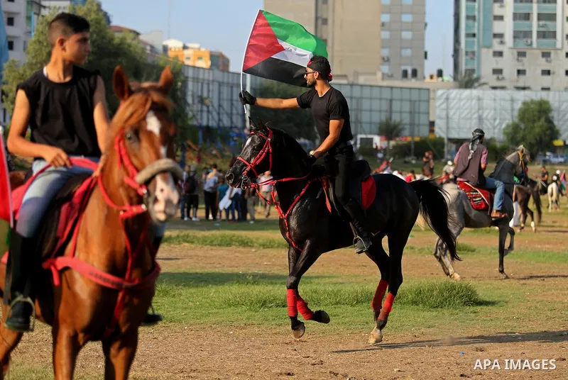 Palestinians hold the national flags as they ride horses during parade of horses in Gaza city on August 2, 2017. Photo by Ashraf Amra