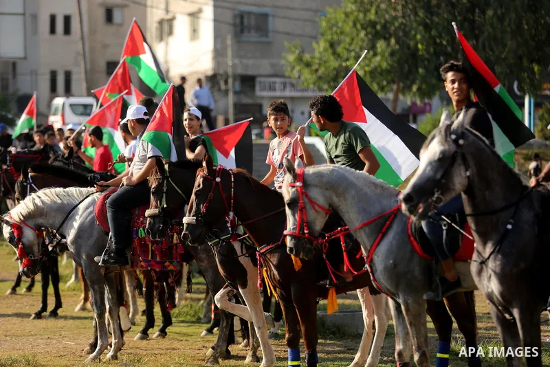 Palestinians hold the national flags as they ride horses during parade of horses in Gaza city on August 2, 2017. Photo by Ashraf Amra