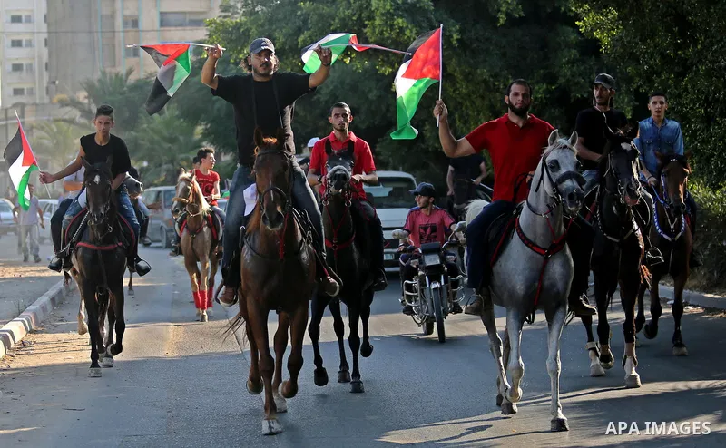 Palestinians hold the national flags as they ride horses during parade of horses in Gaza city on August 2, 2017. Photo by Ashraf Amra