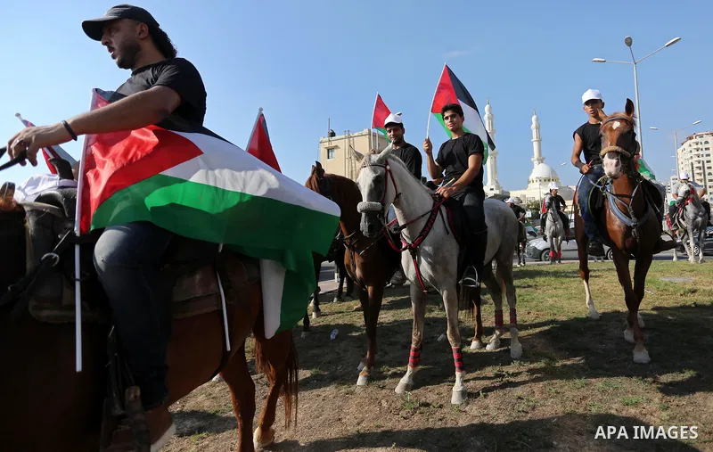 Palestinians hold the national flags as they ride horses during parade of horses in Gaza city on August 2, 2017. Photo by Ashraf Amra