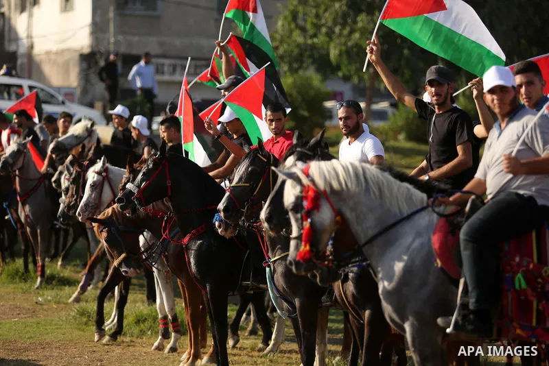 Palestinians hold the national flags as they ride horses during parade of horses in Gaza city on August 2, 2017. Photo by Ashraf Amra