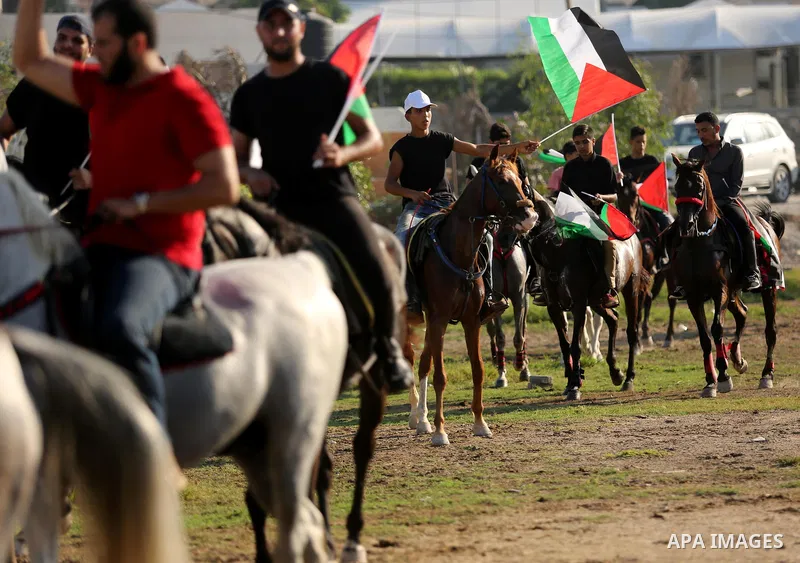 Palestinians hold the national flags as they ride horses during parade of horses in Gaza city on August 2, 2017. Photo by Ashraf Amra