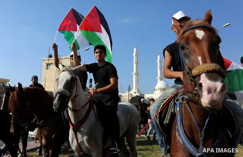 Palestinians hold the national flags as they ride horses during parade of horses in Gaza city on August 2, 2017. Photo by Ashraf Amra