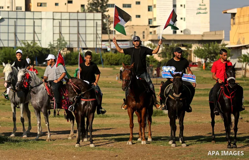 Palestinians hold the national flags as they ride horses during parade of horses in Gaza city on August 2, 2017. Photo by Ashraf Amra