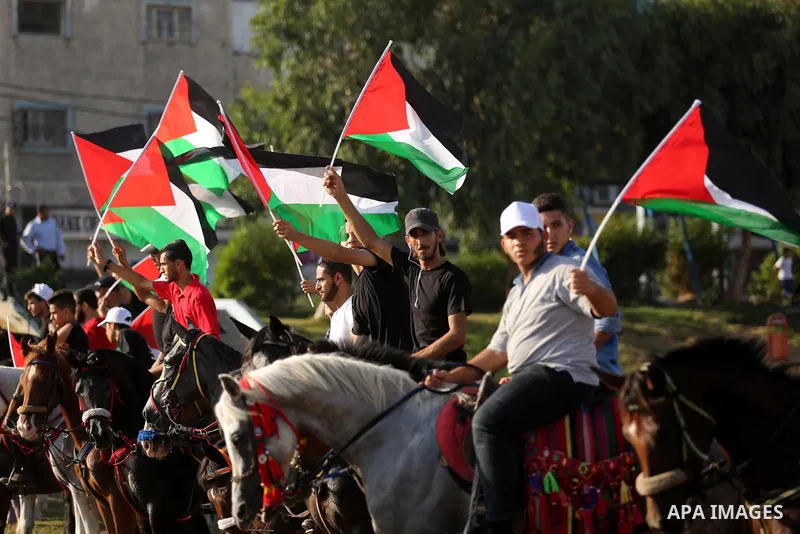 Palestinians hold the national flags as they ride horses during parade of horses in Gaza city on August 2, 2017. Photo by Ashraf Amra