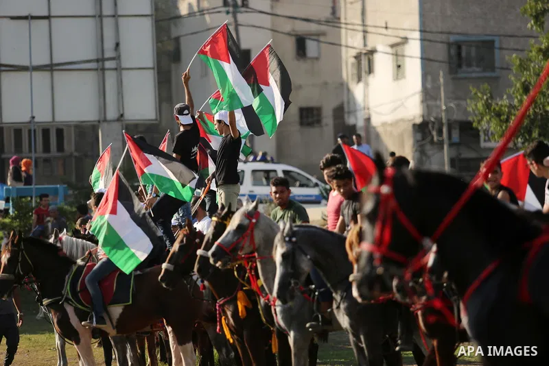 Palestinians hold the national flags as they ride horses during parade of horses in Gaza city on August 2, 2017. Photo by Ashraf Amra
