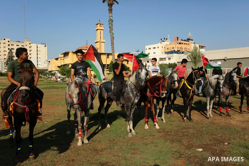 Palestinians hold the national flags as they ride horses during parade of horses in Gaza city on August 2, 2017. Photo by Ashraf Amra