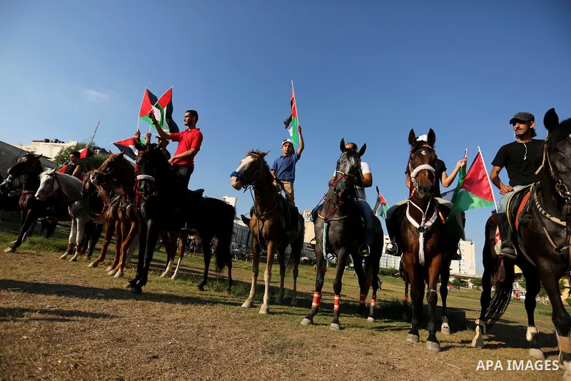 Palestinians hold the national flags as they ride horses during parade of horses in Gaza city on August 2, 2017. Photo by Ashraf Amra