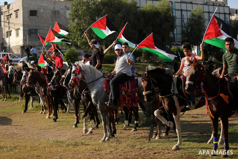 Palestinians hold the national flags as they ride horses during parade of horses in Gaza city on August 2, 2017. Photo by Ashraf Amra