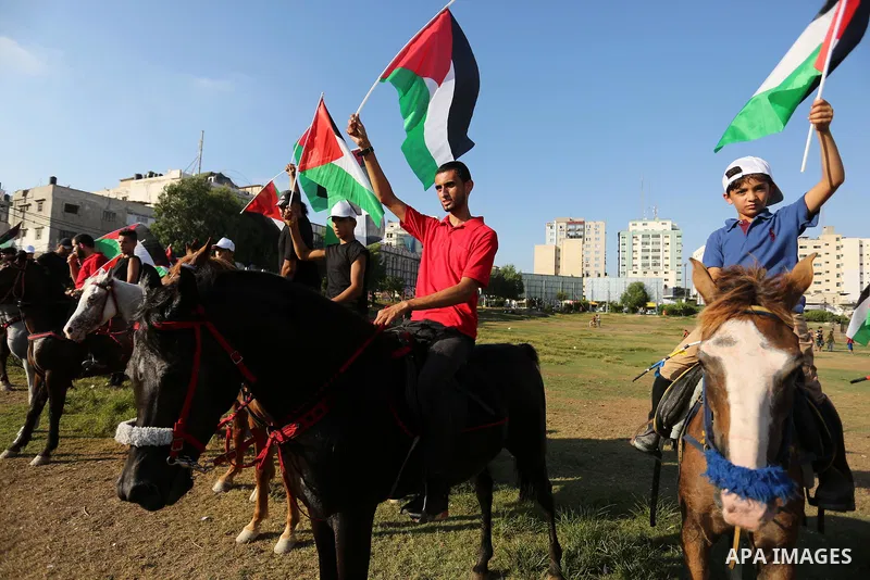 Palestinians hold the national flags as they ride horses during parade of horses in Gaza city on August 2, 2017. Photo by Ashraf Amra