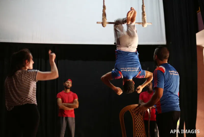 An Irish trainer, Jennifer Higgins, helps a member of Gaza circus to perform during an aerial silks practice class in Gaza City, on August 3, 2017. Photo by Mohammed Asad