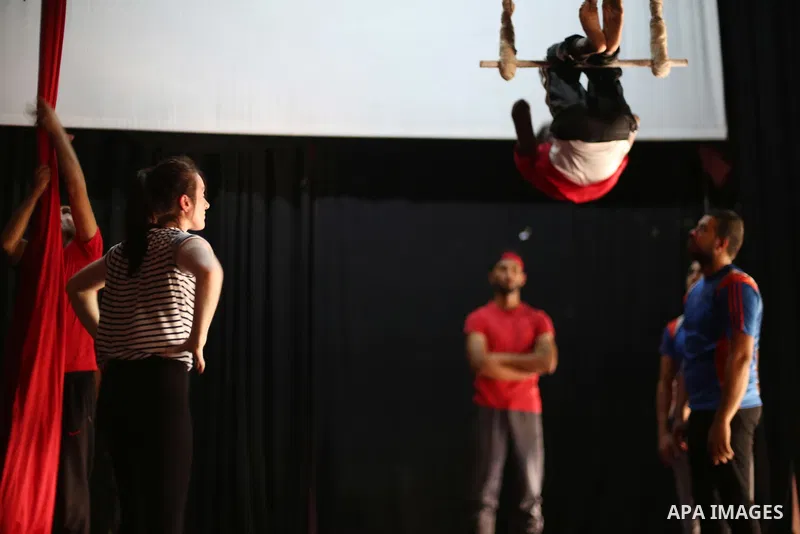 An Irish trainer, Jennifer Higgins, helps a member of Gaza circus to perform during an aerial silks practice class in Gaza City, on August 3, 2017. Photo by Mohammed Asad